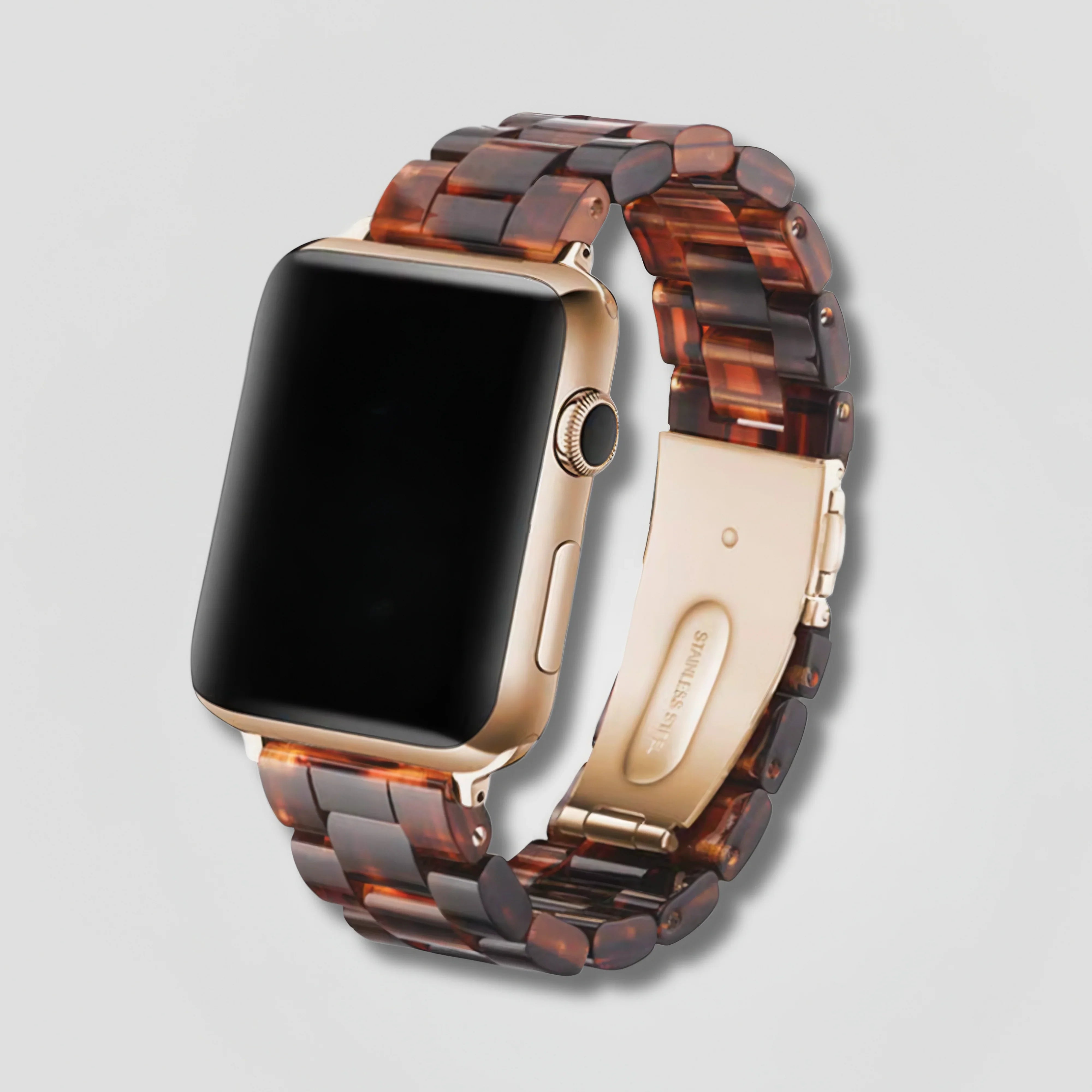 Gold smart watch with tortoiseshell resin link band on a plain light background